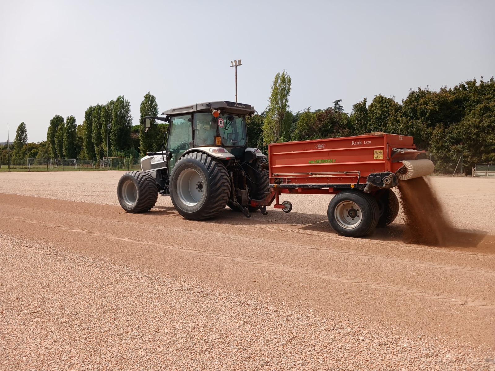 Trattore con spargitore durante la preparazione del sottofondo di un campo